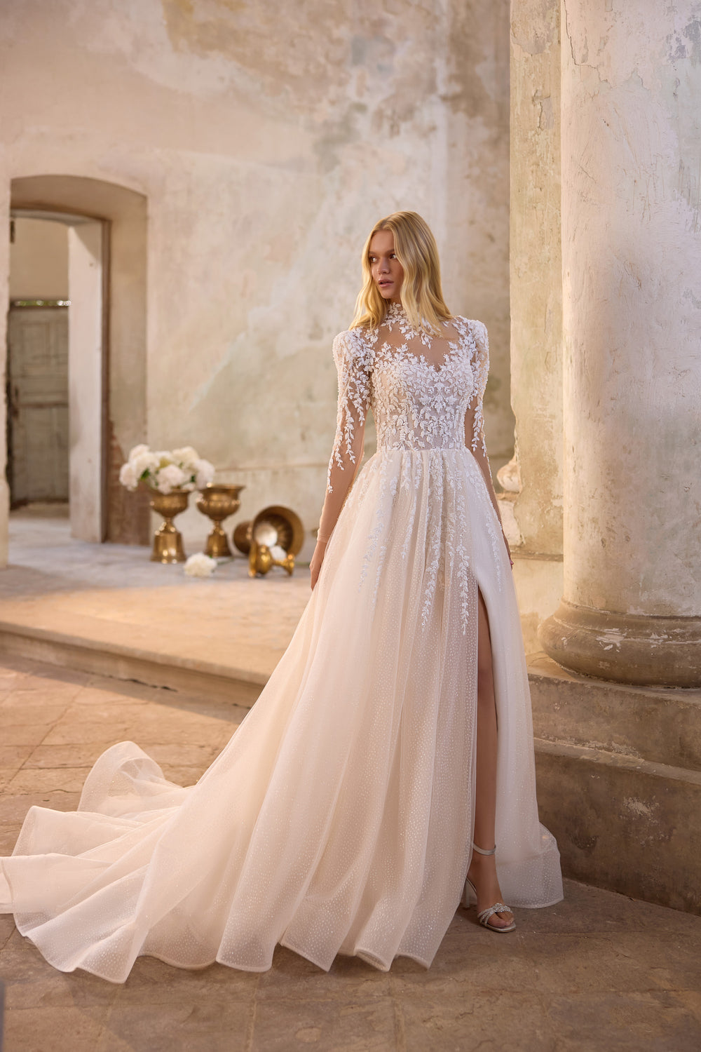 Glamorous mermaid wedding dress featuring sparkling crystal beadwork, dramatic detachable organza sleeves, flowing cape, and a couture-inspired corset silhouette.