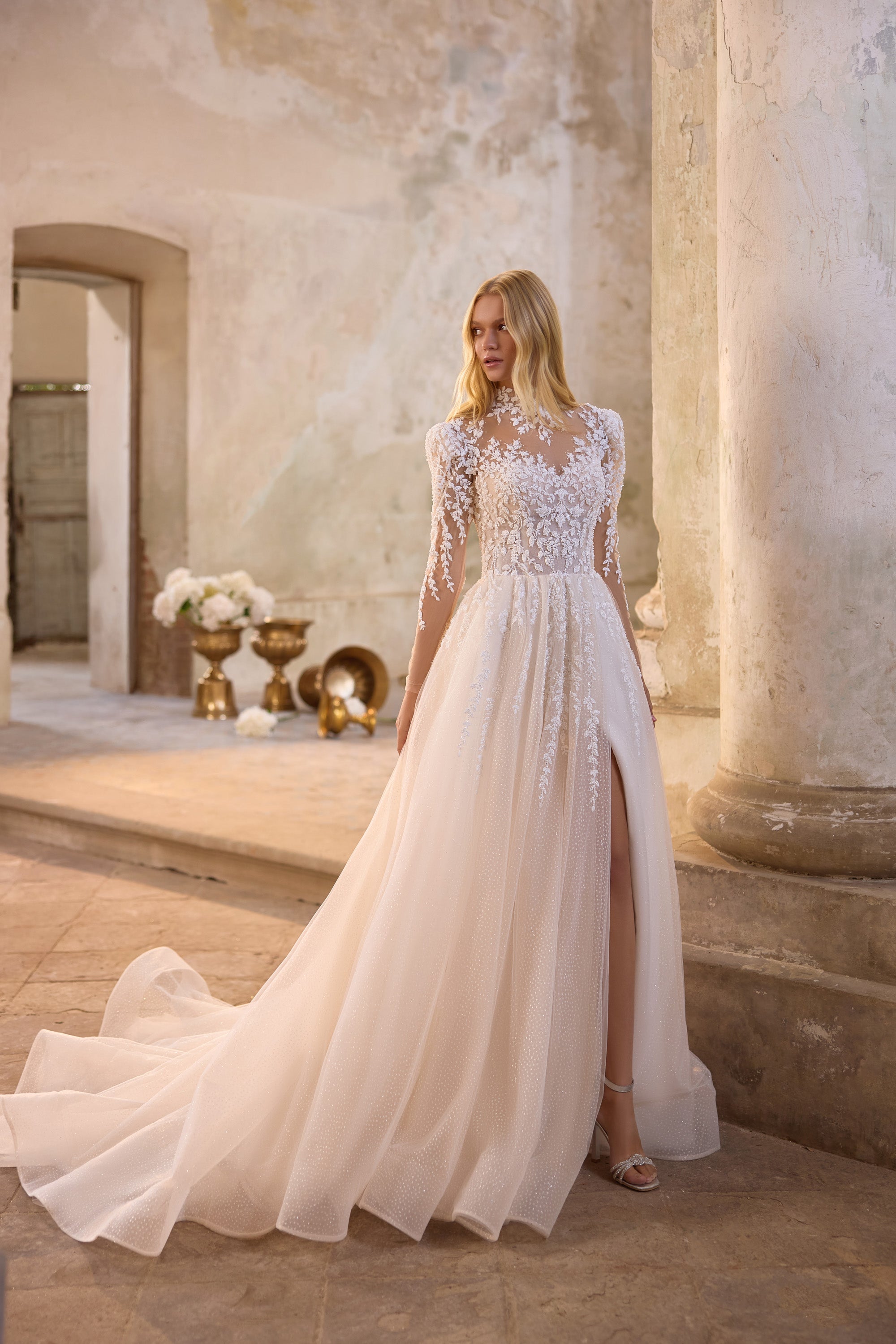 Ivory wedding dress with high neckline, embellished floral lace bodice, long sleeves, and sweeping train