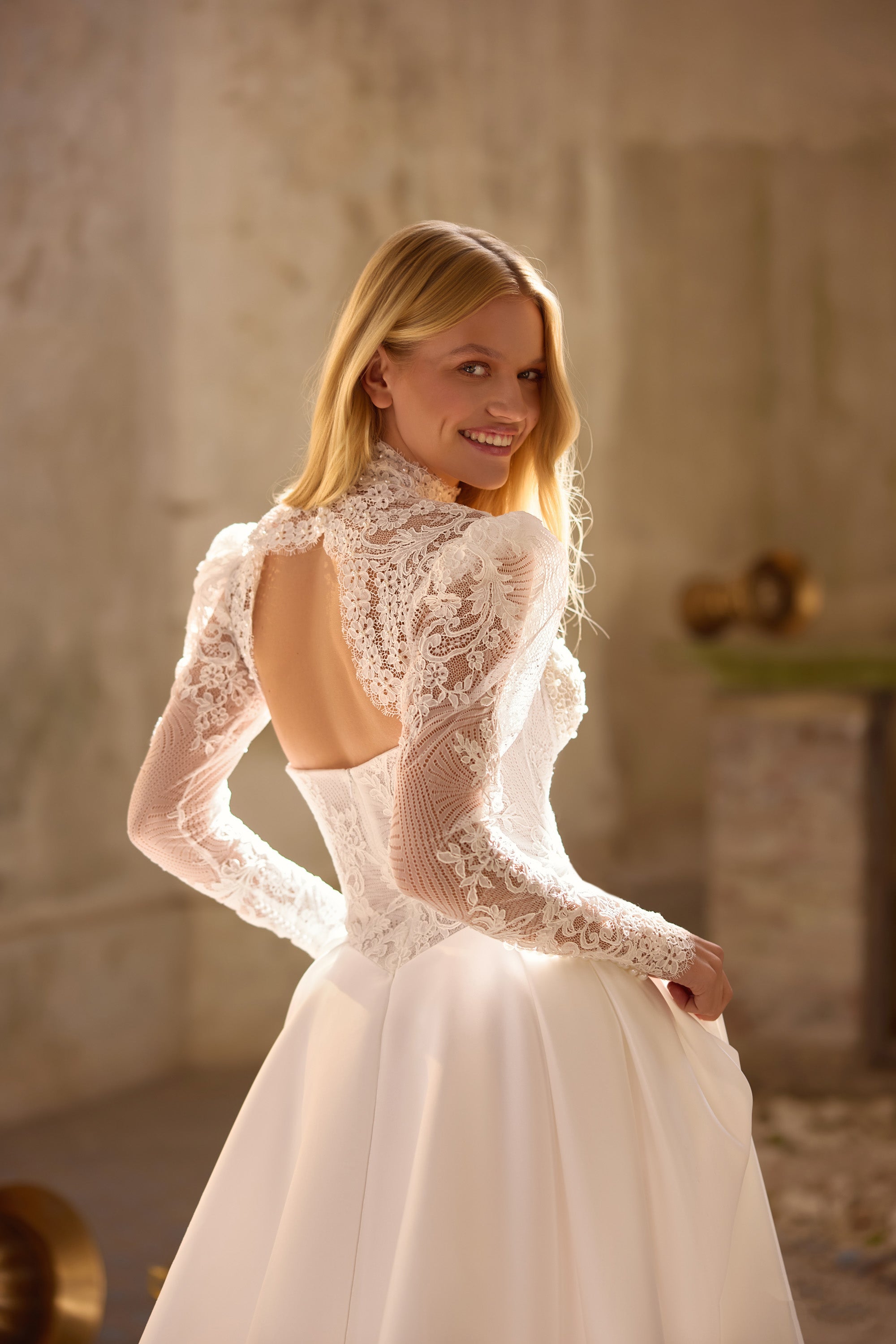 Ivory wedding dress with long lace sleeves, high neck, open back, and flowing A-line skirt