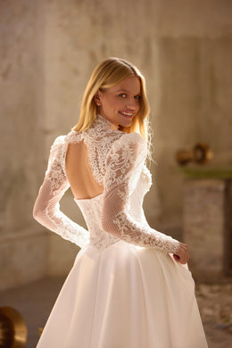 Ivory wedding dress with long lace sleeves, high neck, open back, and flowing A-line skirt