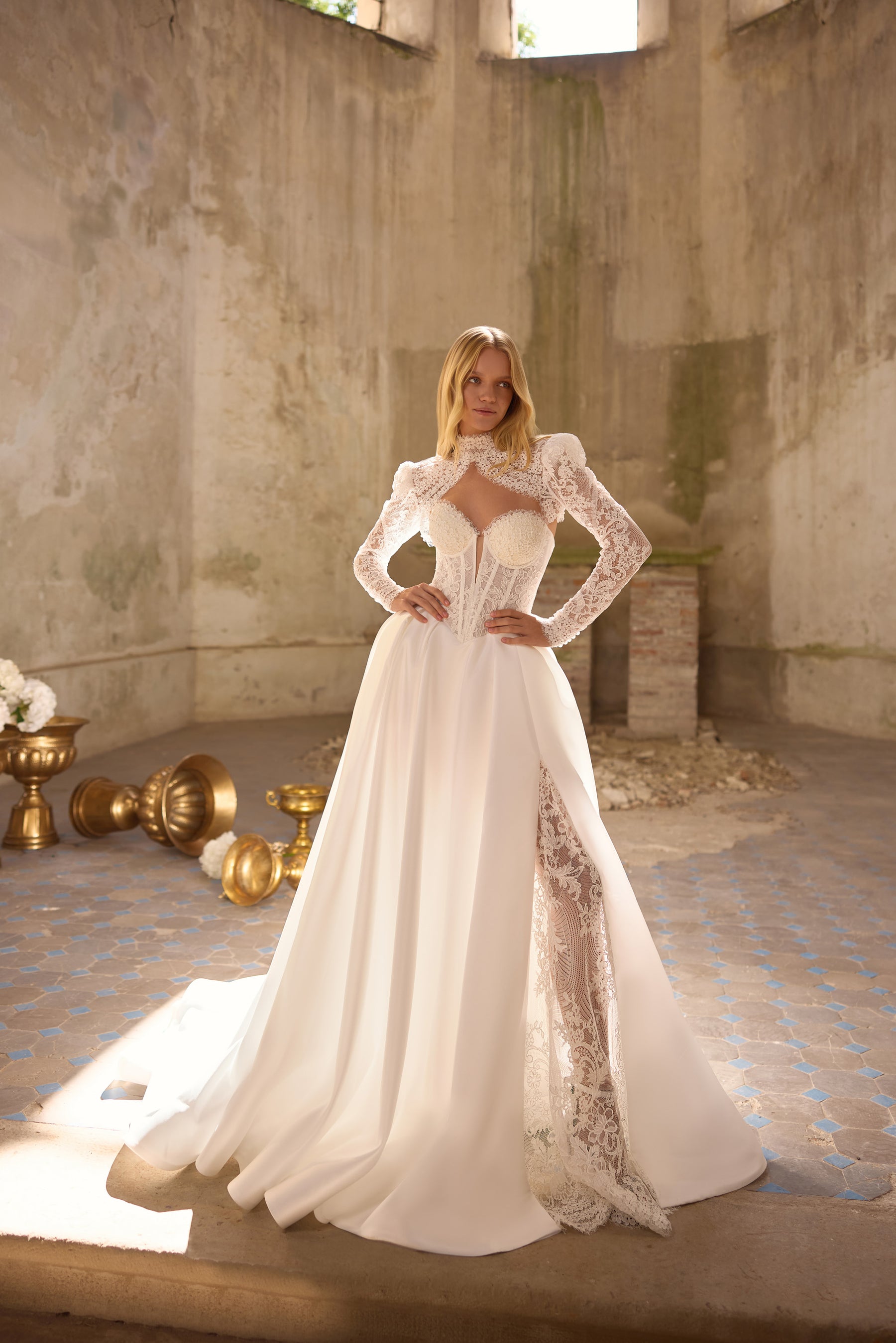 Full-length ivory wedding dress with long lace sleeves, a lace-trimmed slit, and sweeping train