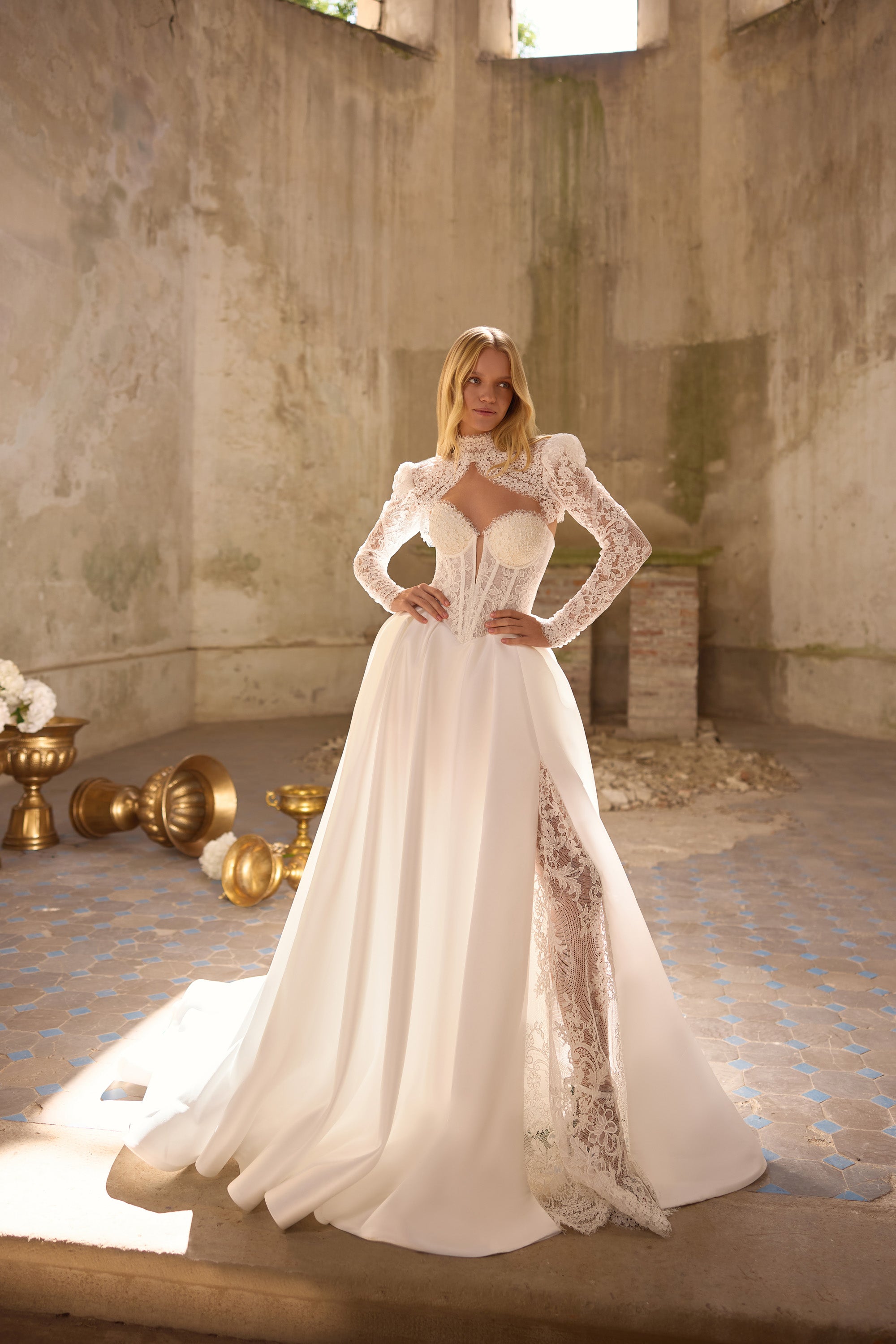 Full-length ivory wedding dress with long lace sleeves, a lace-trimmed slit, and sweeping train