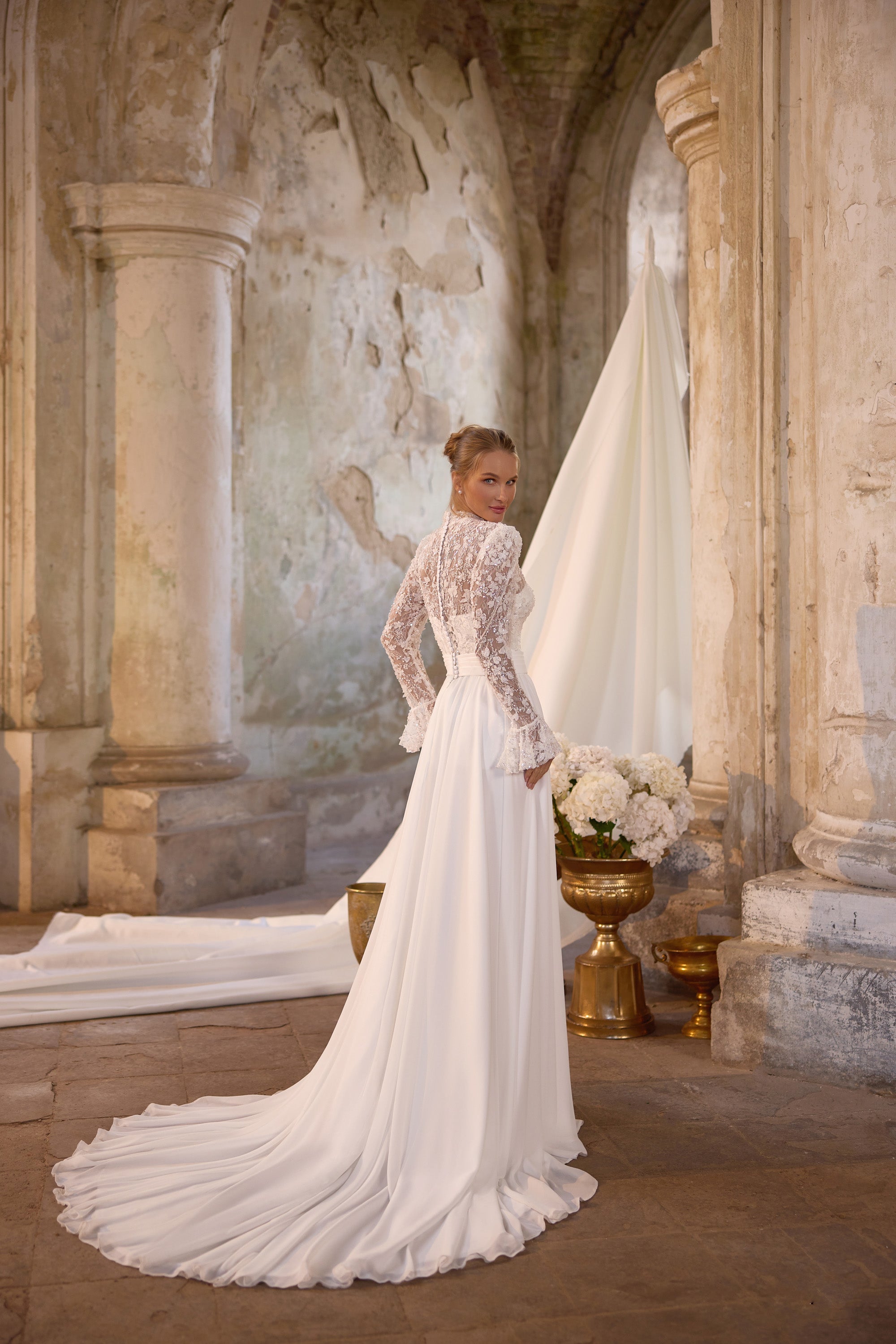 Ivory wedding dress with a fitted lace bodice, long sleeves, and a sweeping floor-length train