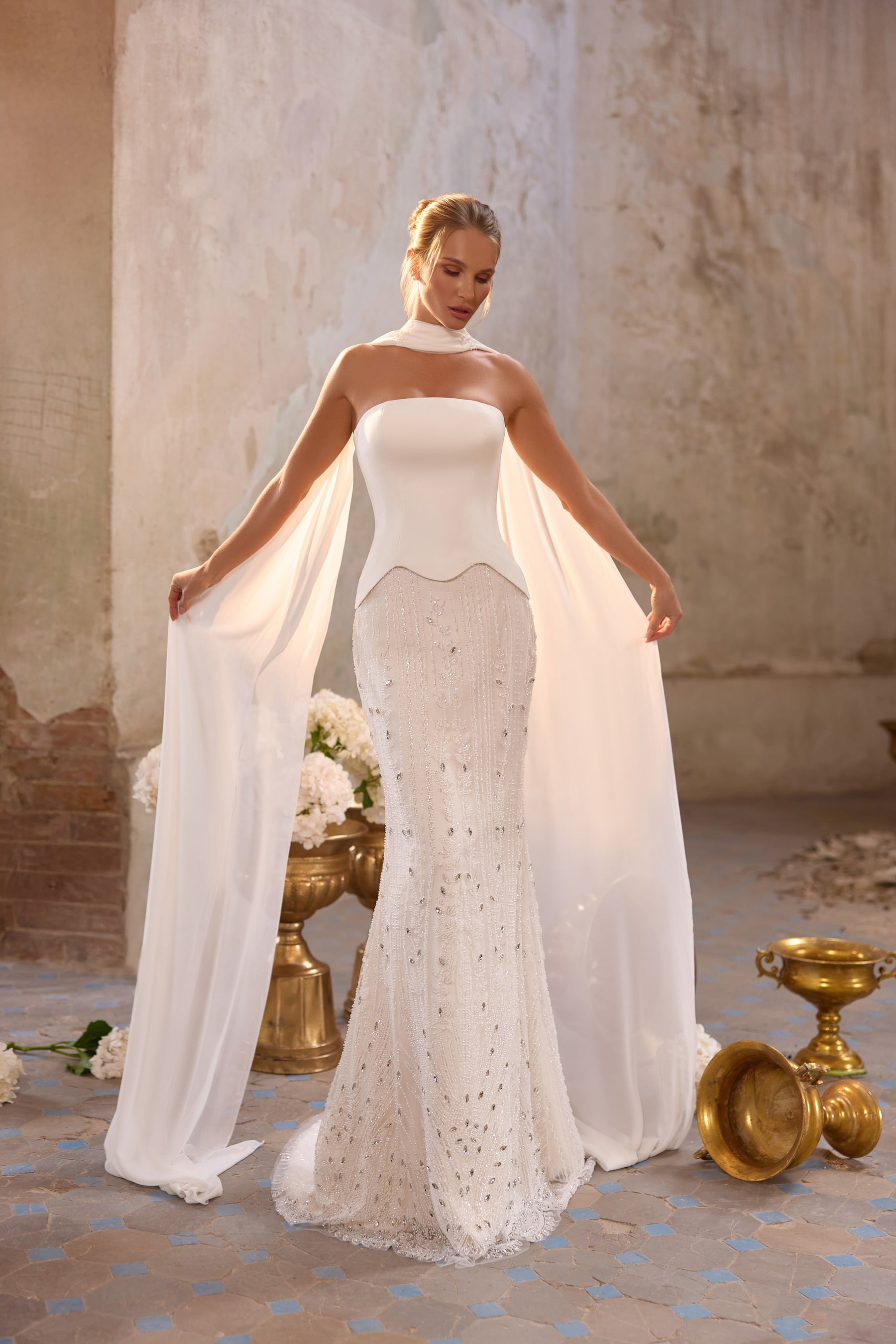 Ivory wedding dress with a strapless bodice, fitted sparkling mermaid skirt, and long chiffon cape