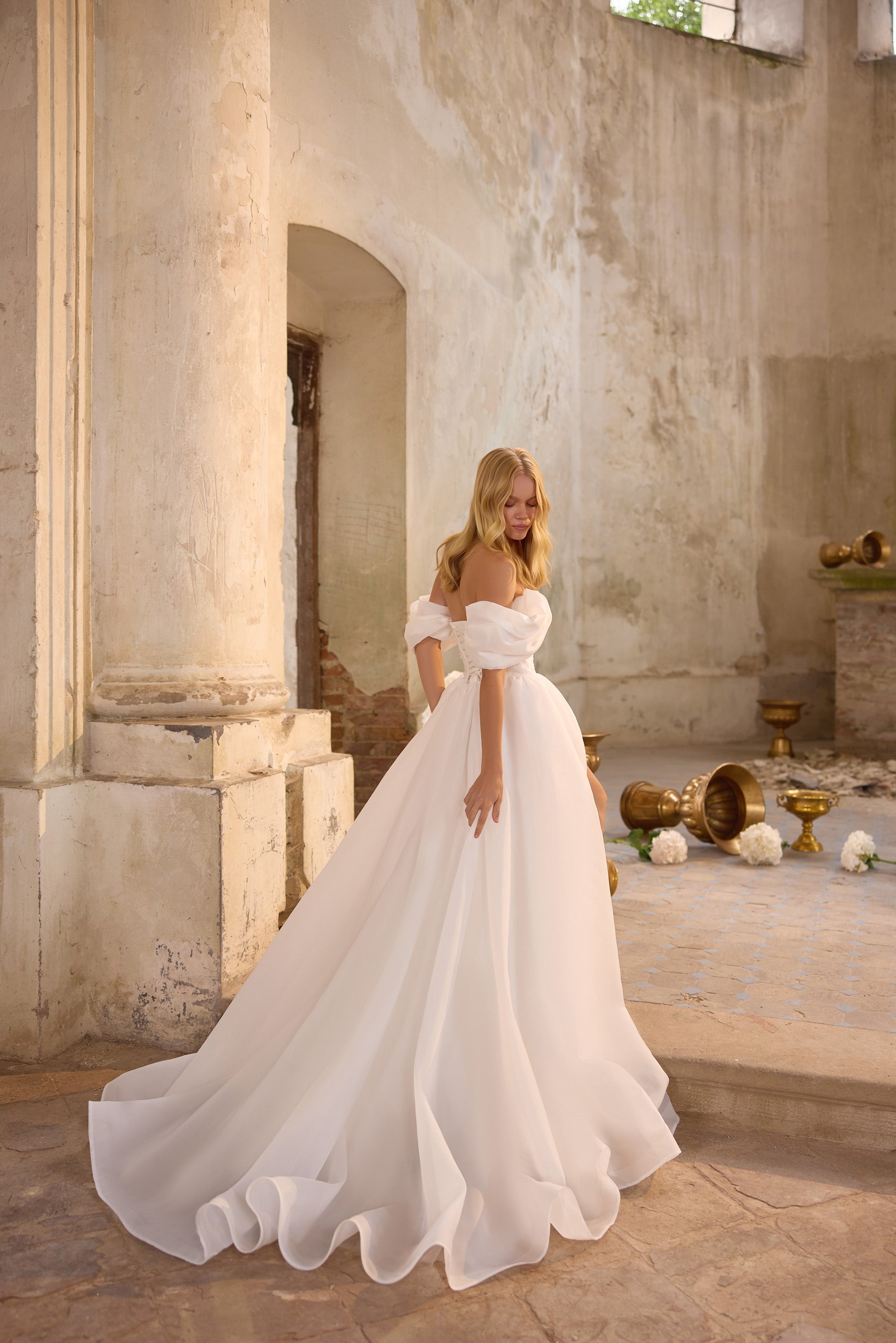 White A-line wedding dress with an off-the-shoulder neckline, puff sleeves, and a sweeping train