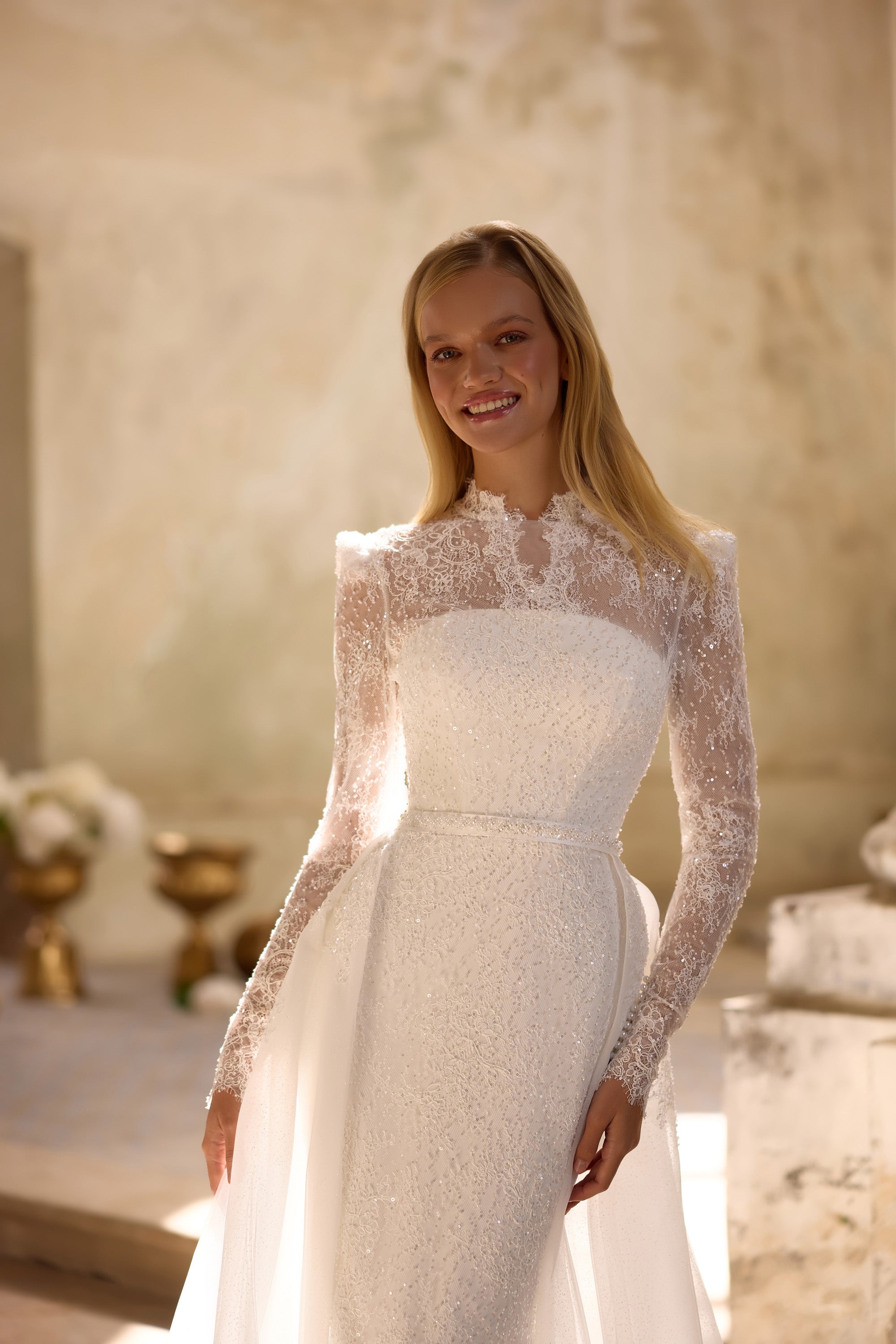 Ivory wedding dress featuring a high illusion neckline, sheer lace sleeves, and a fitted beaded bodice