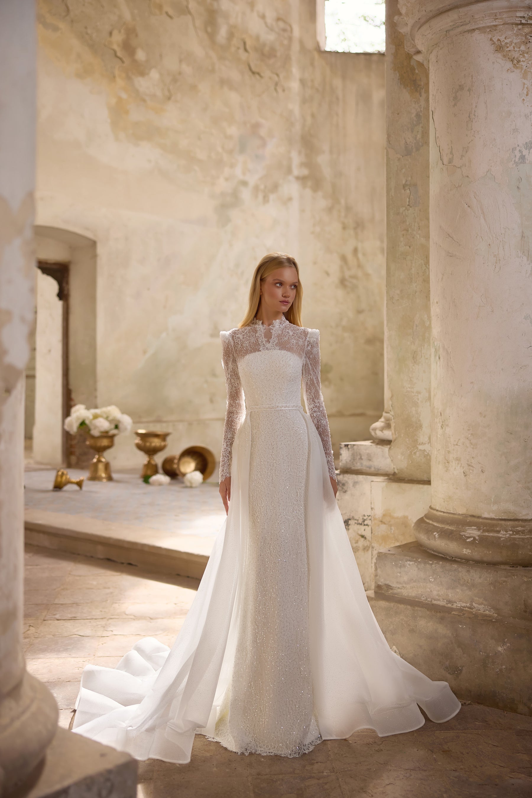 Ivory wedding dress with a fitted beaded gown and flowing overskirt extending into a long train