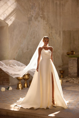 Ivory satin wedding dress with an asymmetric neckline, high thigh slit, and flowing overskirt