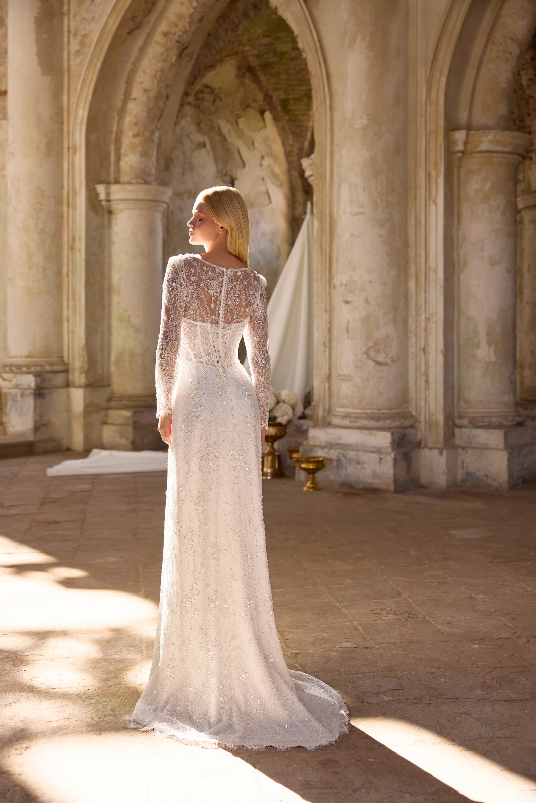 Ivory mermaid wedding dress with a sheer lace back, long sleeves, beadwork, and a sweeping train
