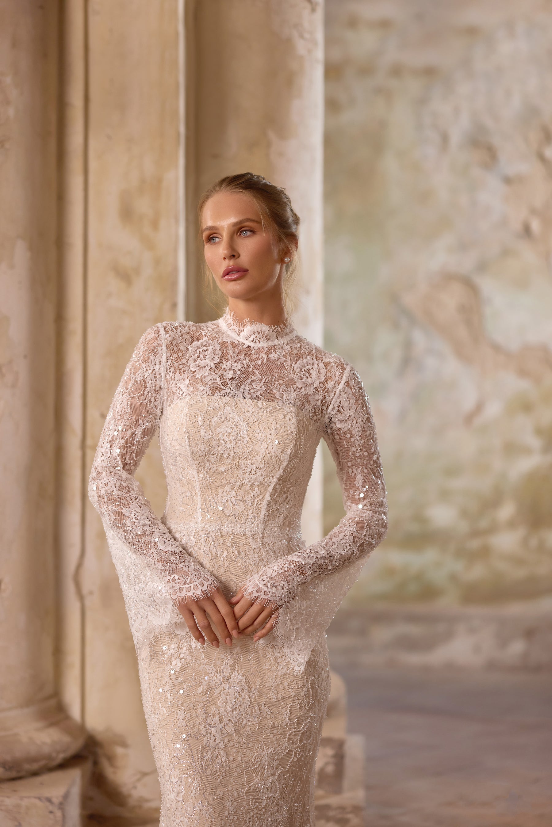 Close-up of the fitted lace bodice on an ivory wedding dress, featuring a high neckline and sheer long sleeves