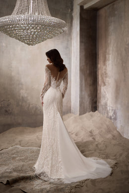 Ivory wedding dress with a deep V back, beaded long sleeves, fitted skirt, and flowing train