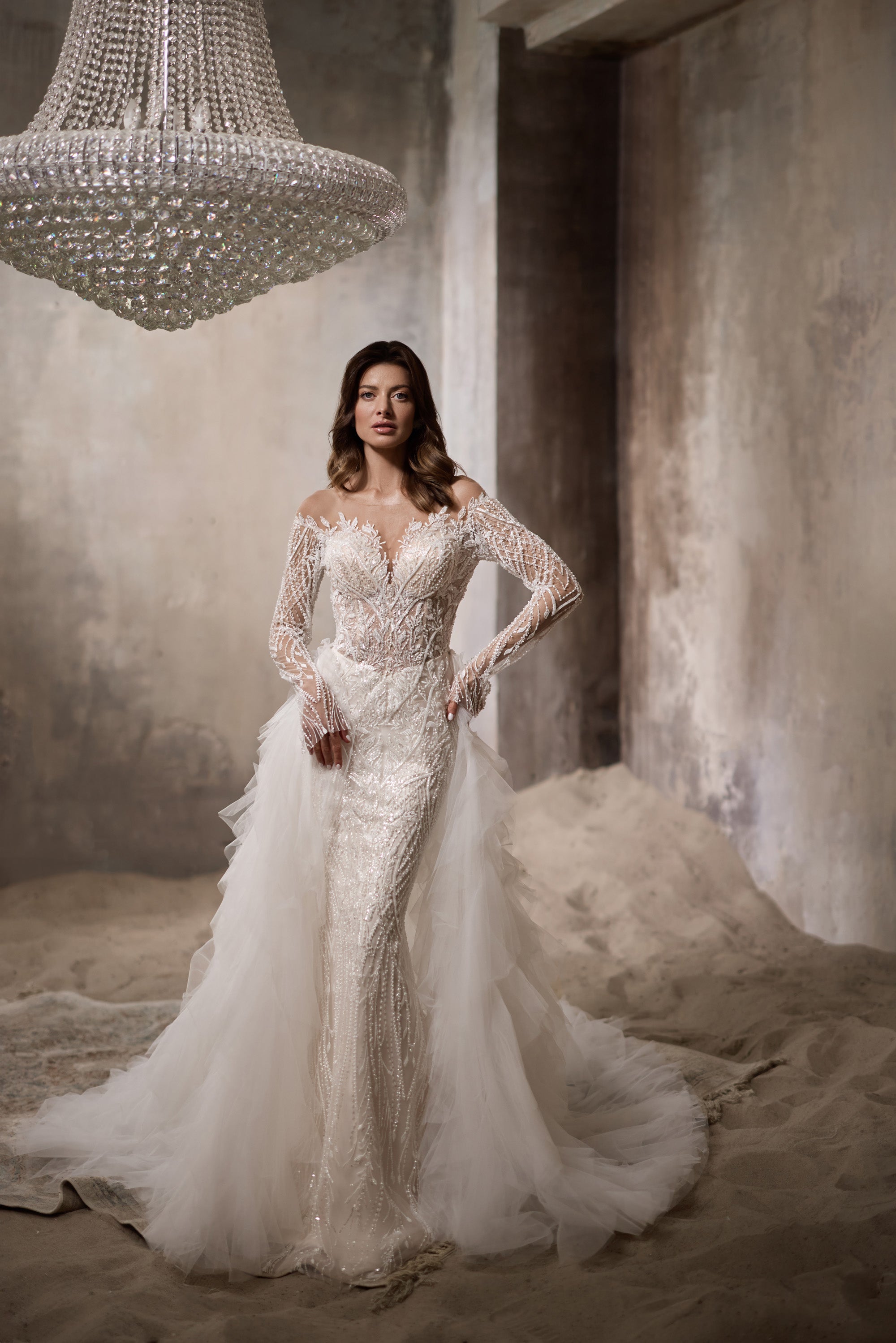 Ivory wedding dress with a beaded lace bodice, long sleeves, fitted silhouette, and tulle overskirt