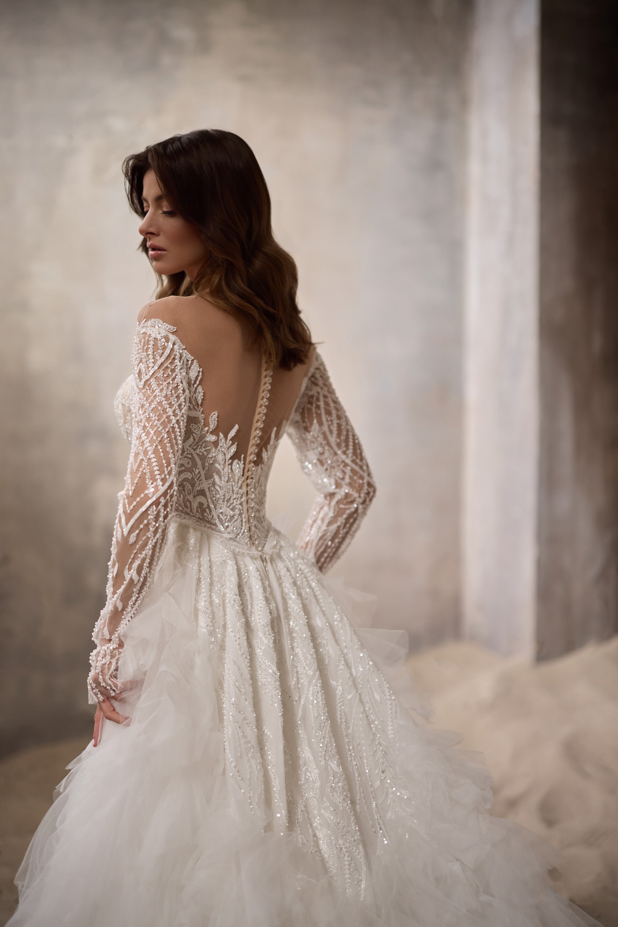 Wedding dress with a sheer beaded back, long lace sleeves, and a full layered tulle overskirt