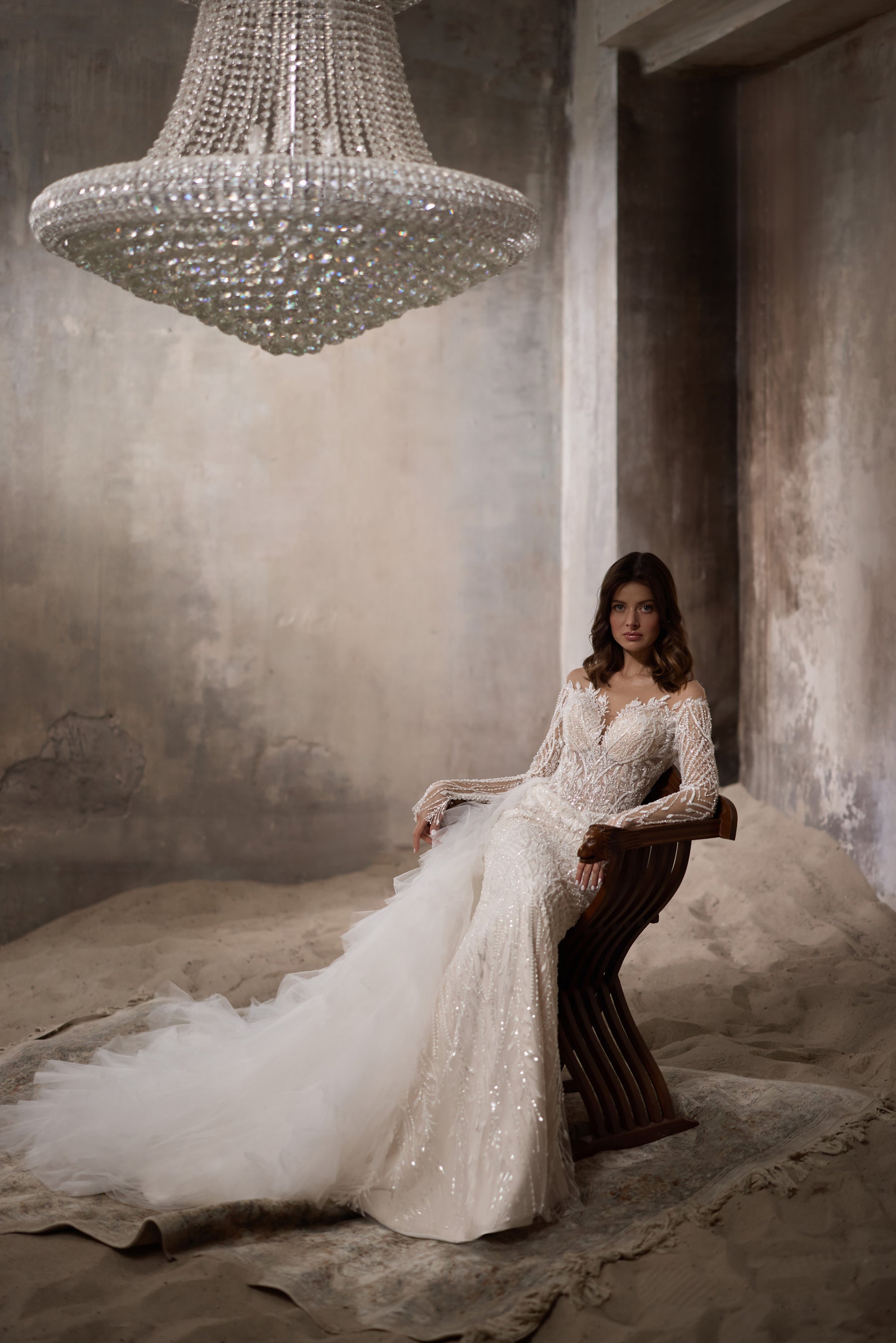 Ivory wedding dress with a fitted beaded bodice, long sleeves, and a sweeping tulle train