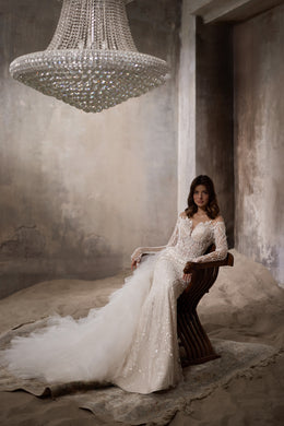 Ivory wedding dress with a fitted beaded bodice, long sleeves, and a sweeping tulle train