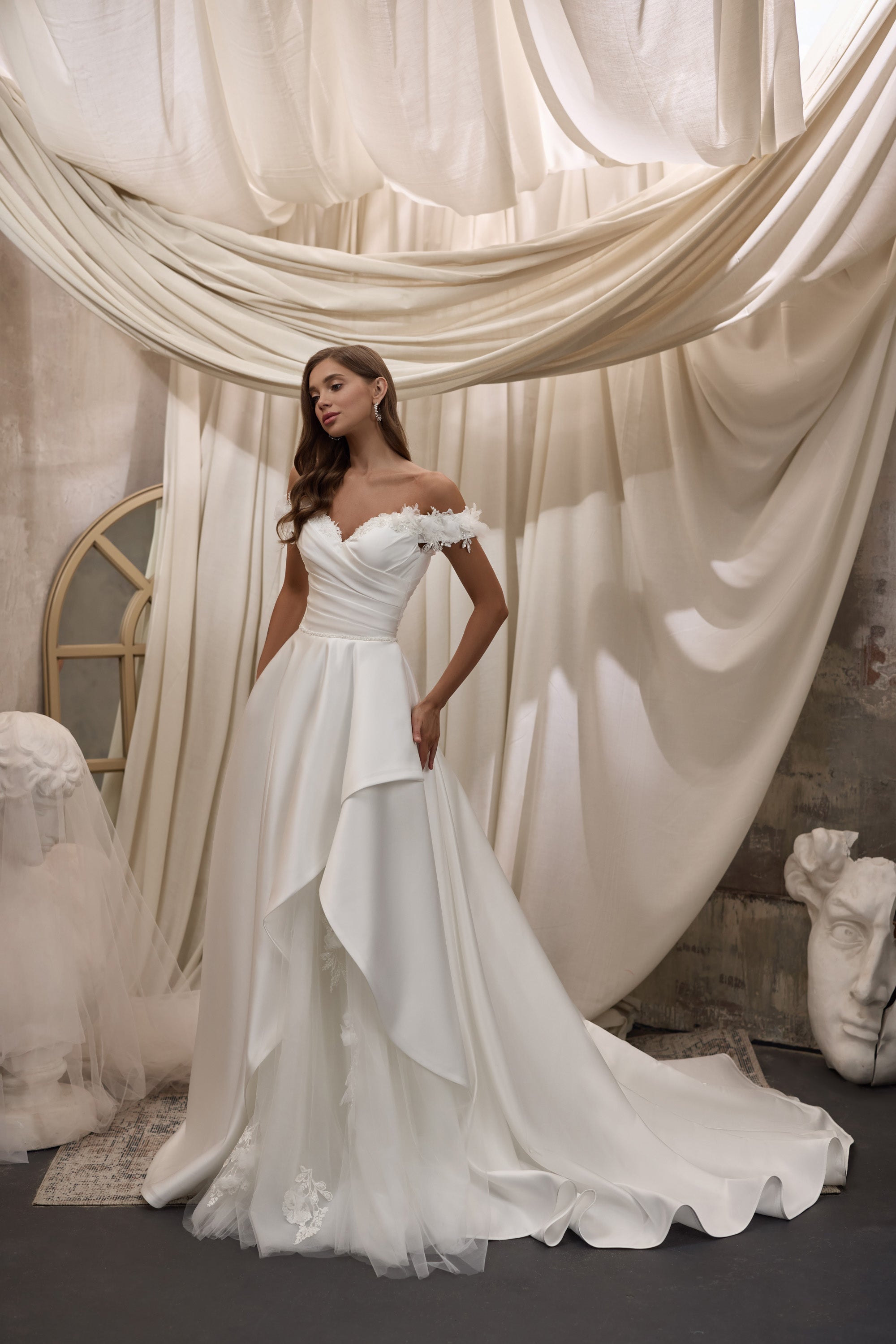 Ivory A-line wedding dress with a sweetheart neckline, ruched bodice, floral appliqués, and layered train