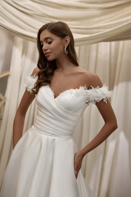 Close-up of an ivory wedding dress bodice with draped ruching, sweetheart neckline, and floral shoulder appliqués