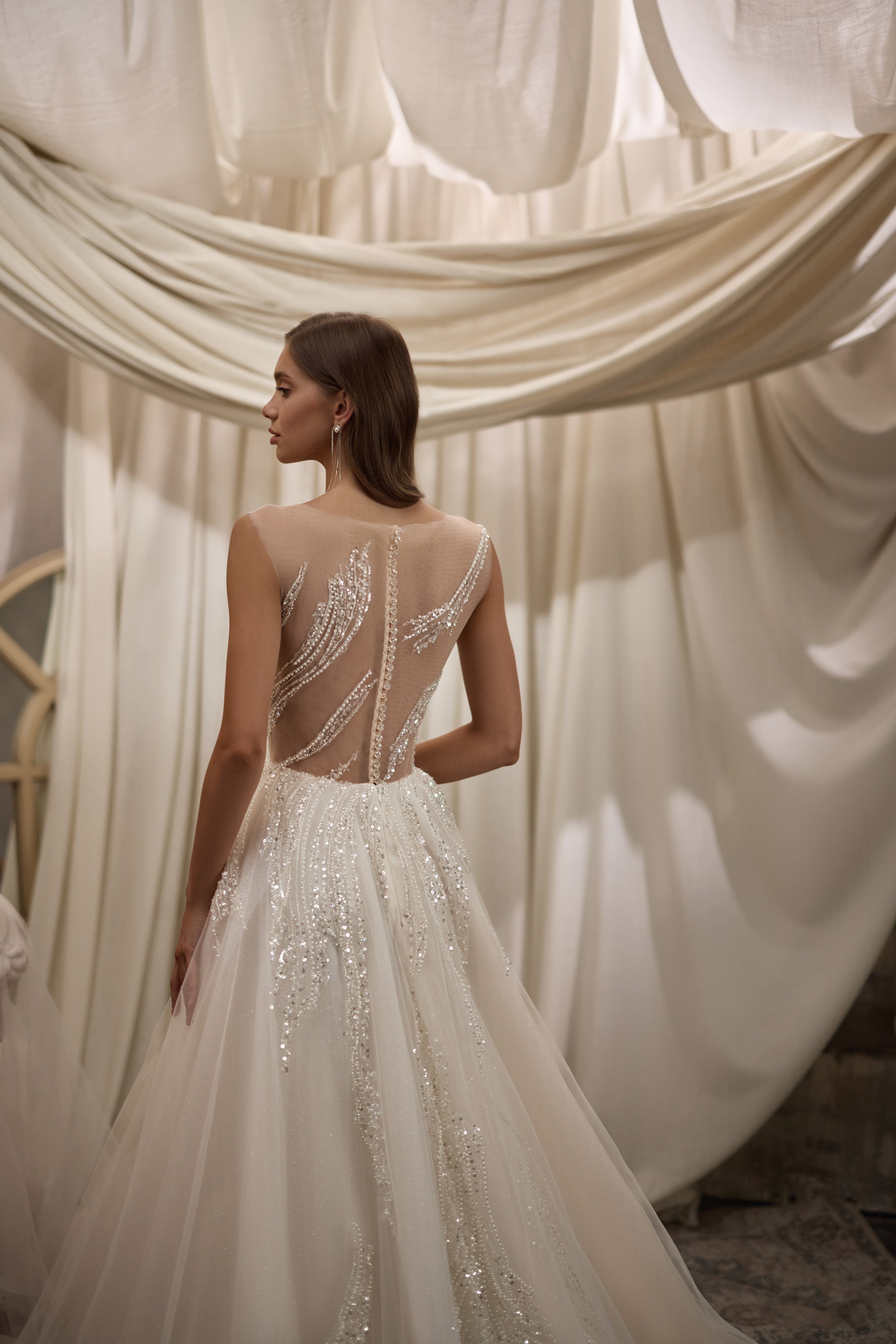Ivory wedding dress with a sheer beaded back, sparkling embellishment, and flowing A-line skirt