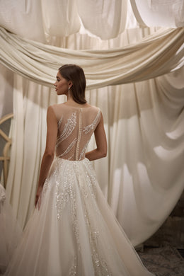 Ivory wedding dress with a sheer beaded back, sparkling embellishment, and flowing A-line skirt