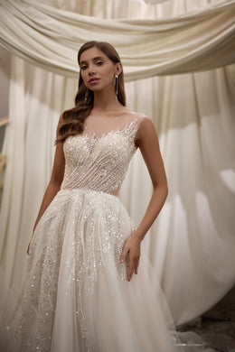 Close-up of a square-neck wedding dress with intricate beadwork across the bodice and skirt