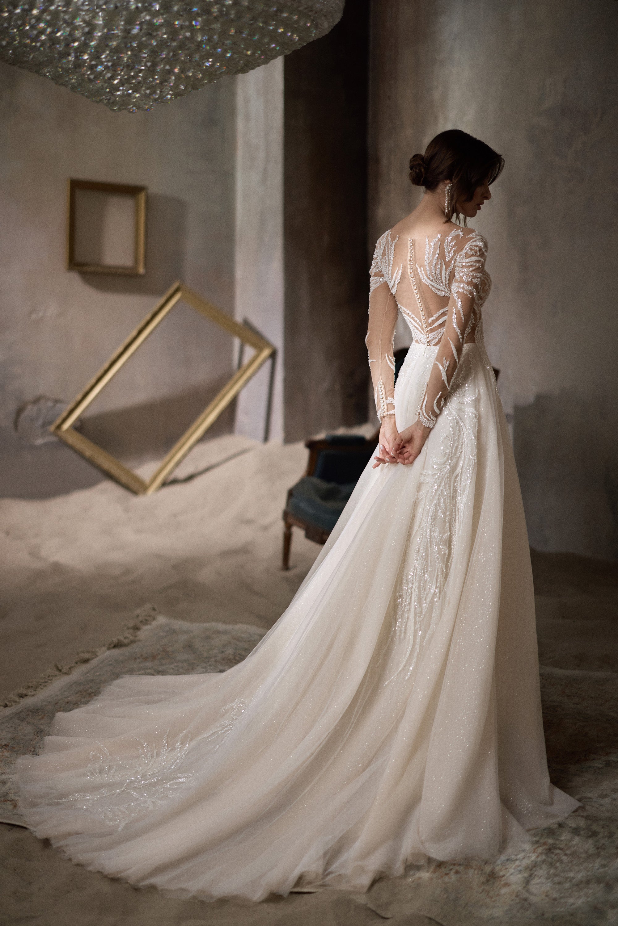 Ivory wedding dress with a sheer beaded back, long sleeves, and a sweeping train