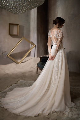 Ivory wedding dress with a sheer beaded back, long sleeves, and a sweeping train