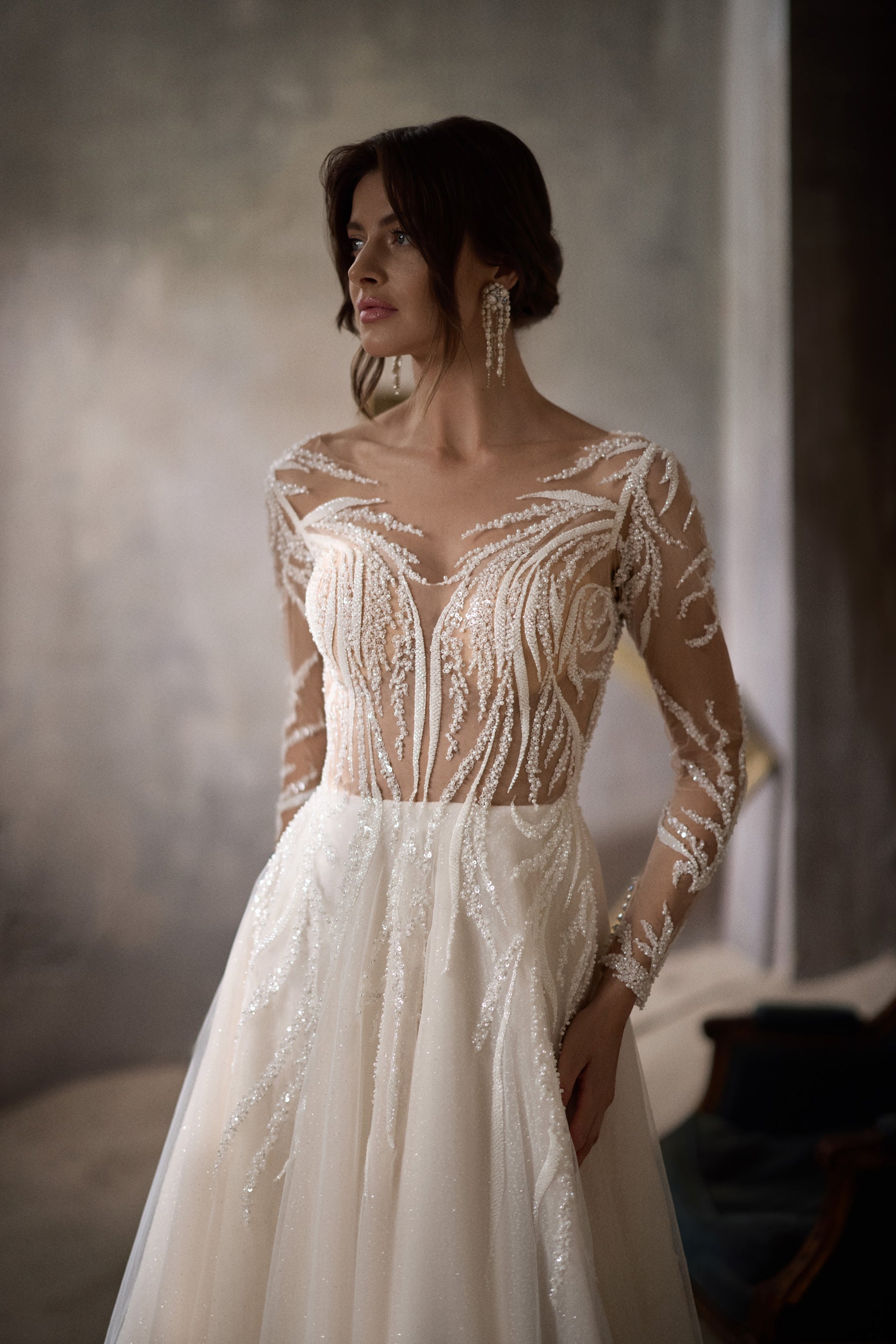 Close-up of an illusion neckline and swirling beadwork on an ivory wedding dress bodice