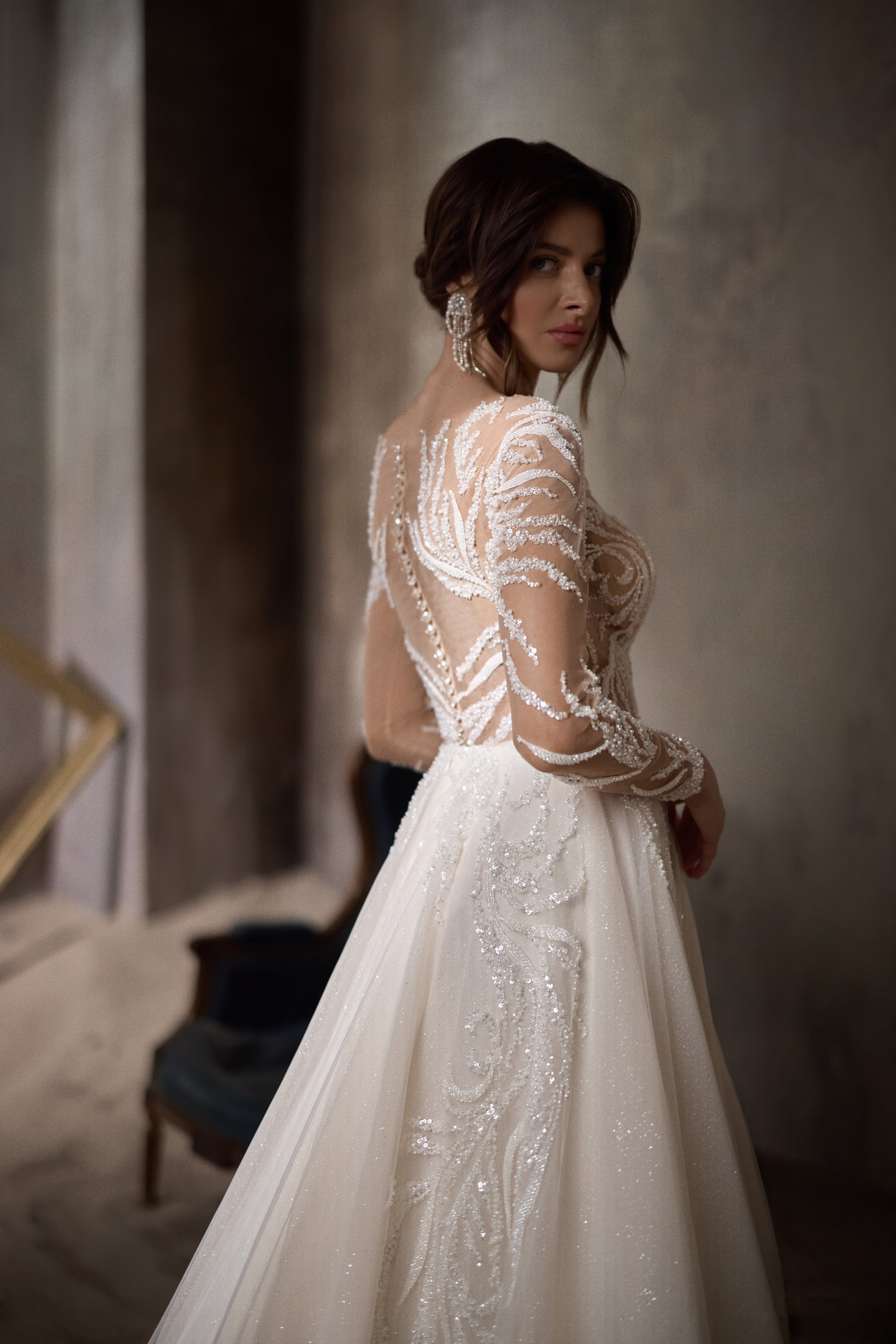 Sheer beaded back and long sleeves on an ivory wedding dress with a flowing train