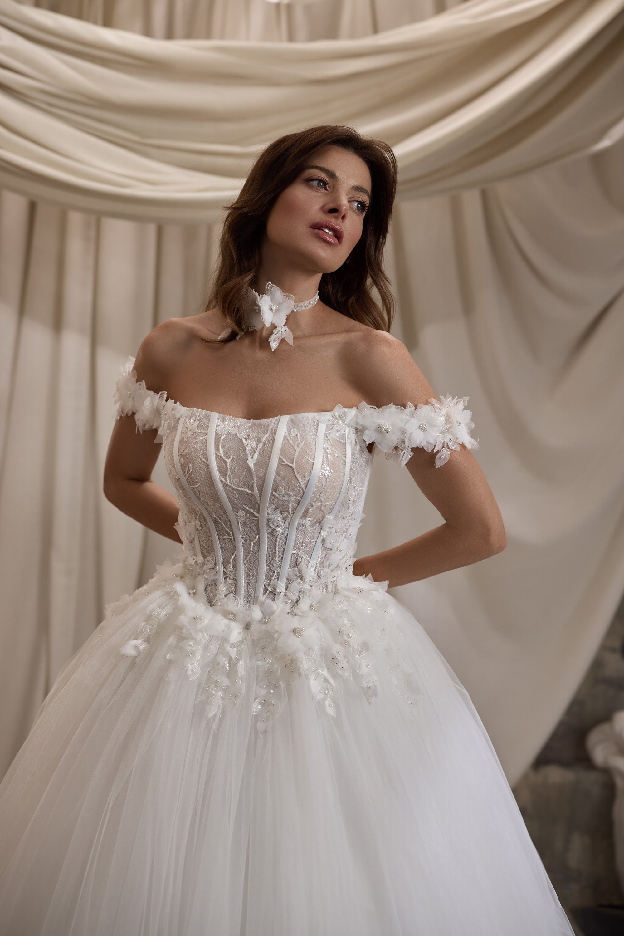 Close-up of a wedding dress with floral off-shoulder appliqués, structured bodice, and sparkling details