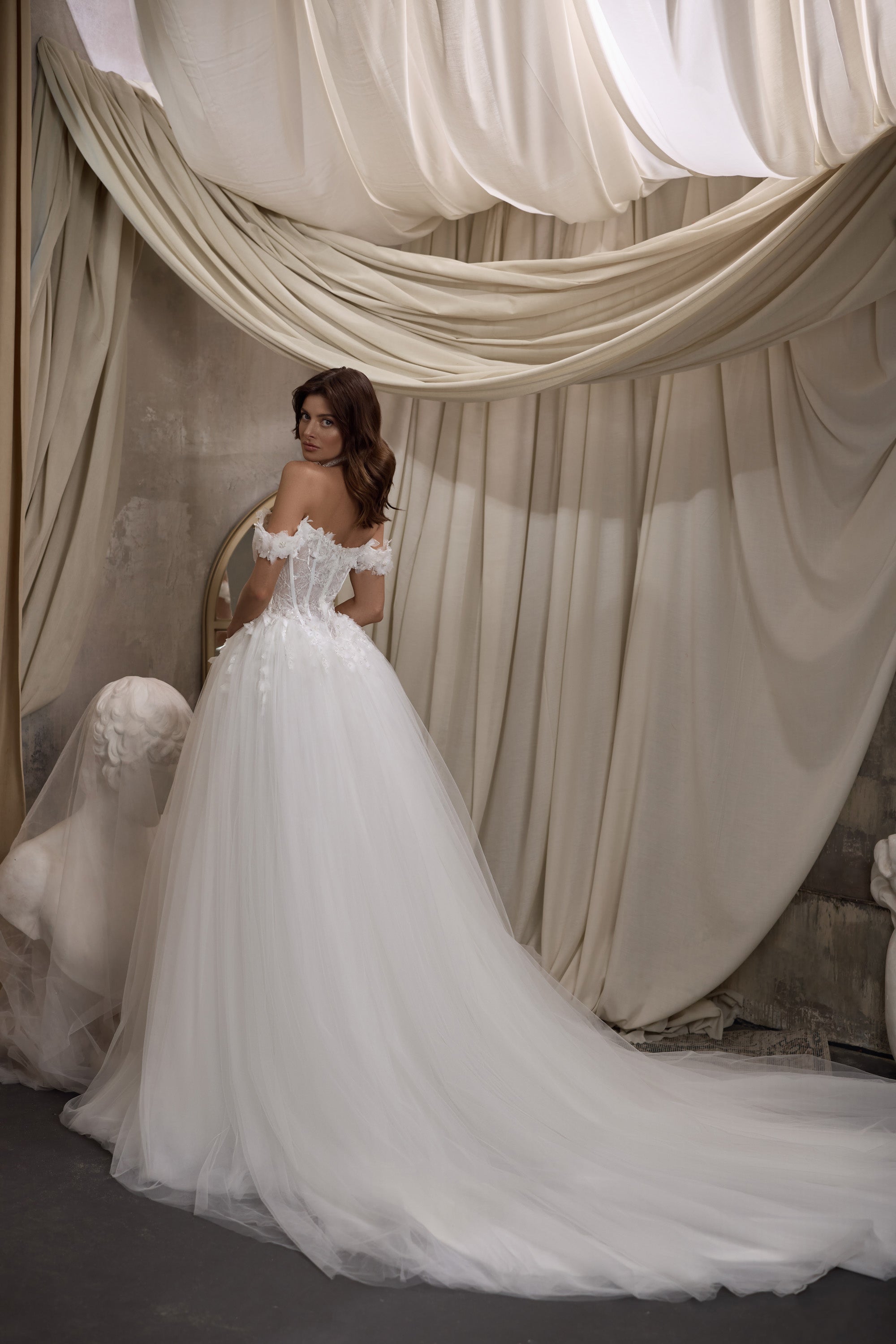 White wedding dress with an off-shoulder floral bodice, full skirt, and long trailing train