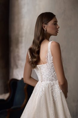 Ivory wedding dress showing an open back with covered buttons and a shimmering A-line skirt