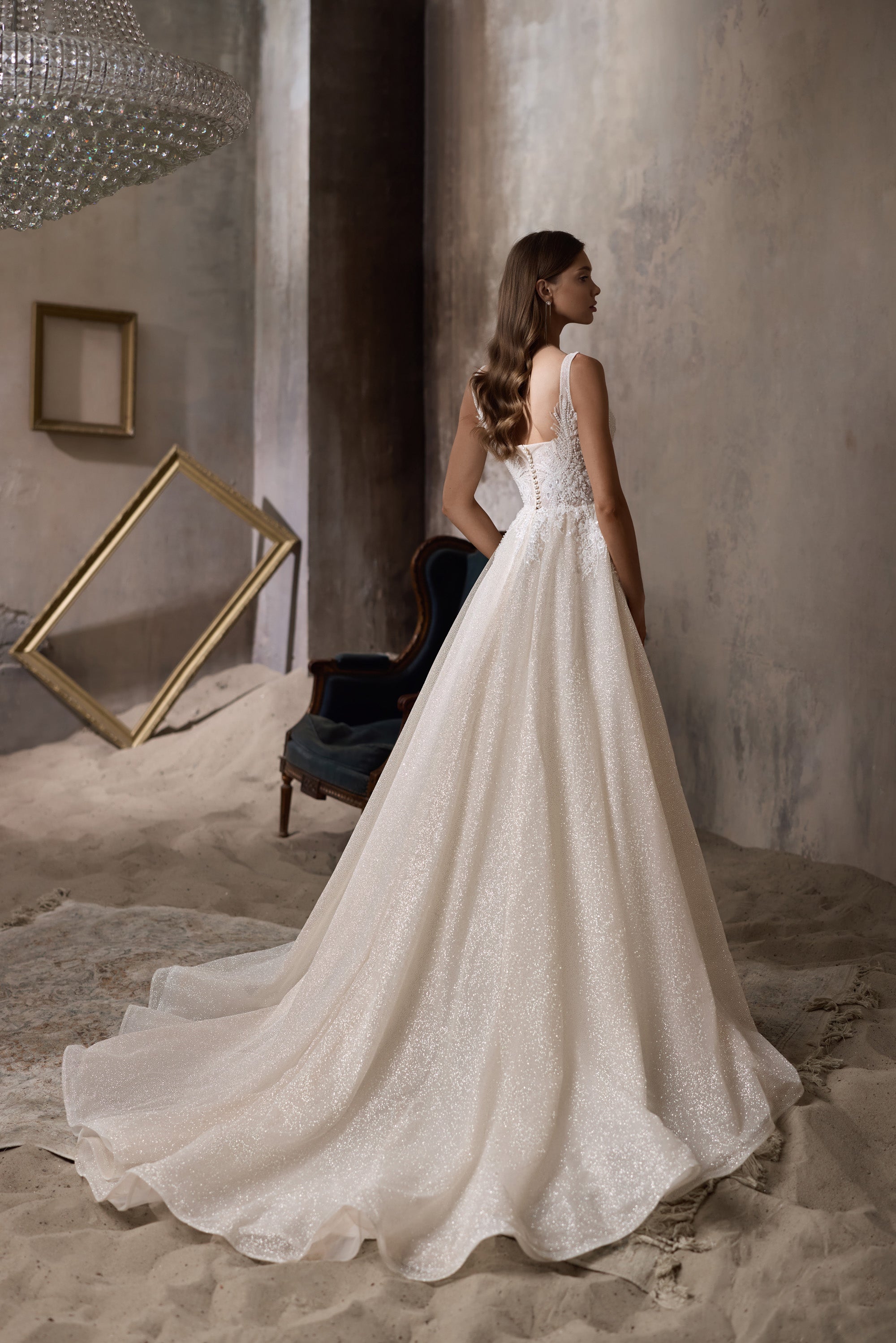 Open back and flowing train on an ivory A-line wedding dress with a sparkling full skirt