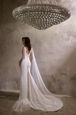 Open V-back wedding dress with floral lace, a long sheer cape, and an extended train