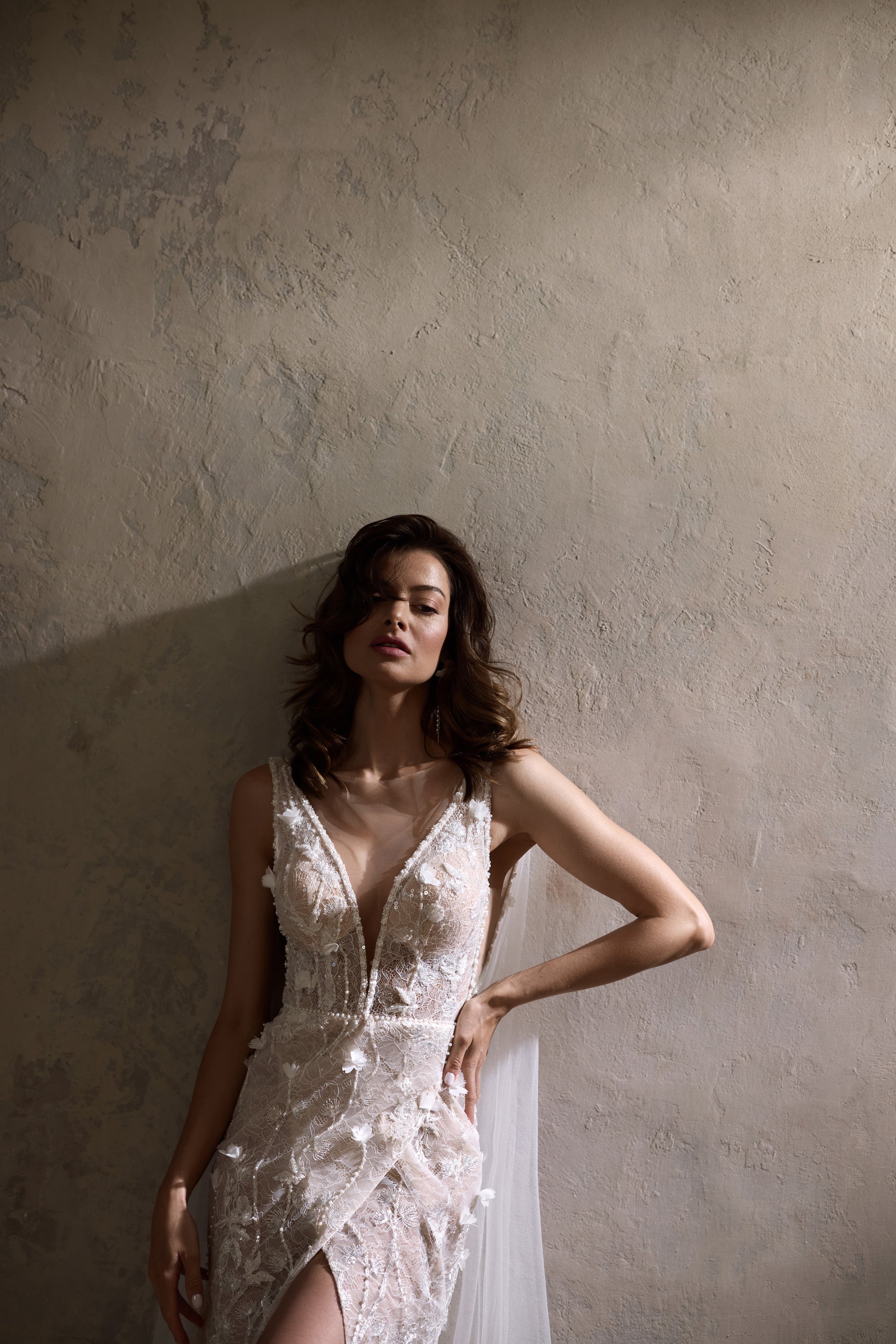 Close-up of a wedding dress bodice with a plunging V-neck, thin straps, floral lace, and shimmering beadwork