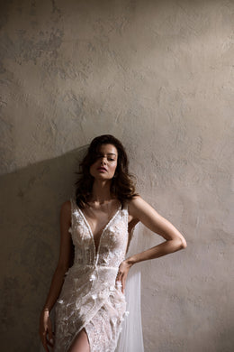 Close-up of a wedding dress bodice with a plunging V-neck, thin straps, floral lace, and shimmering beadwork