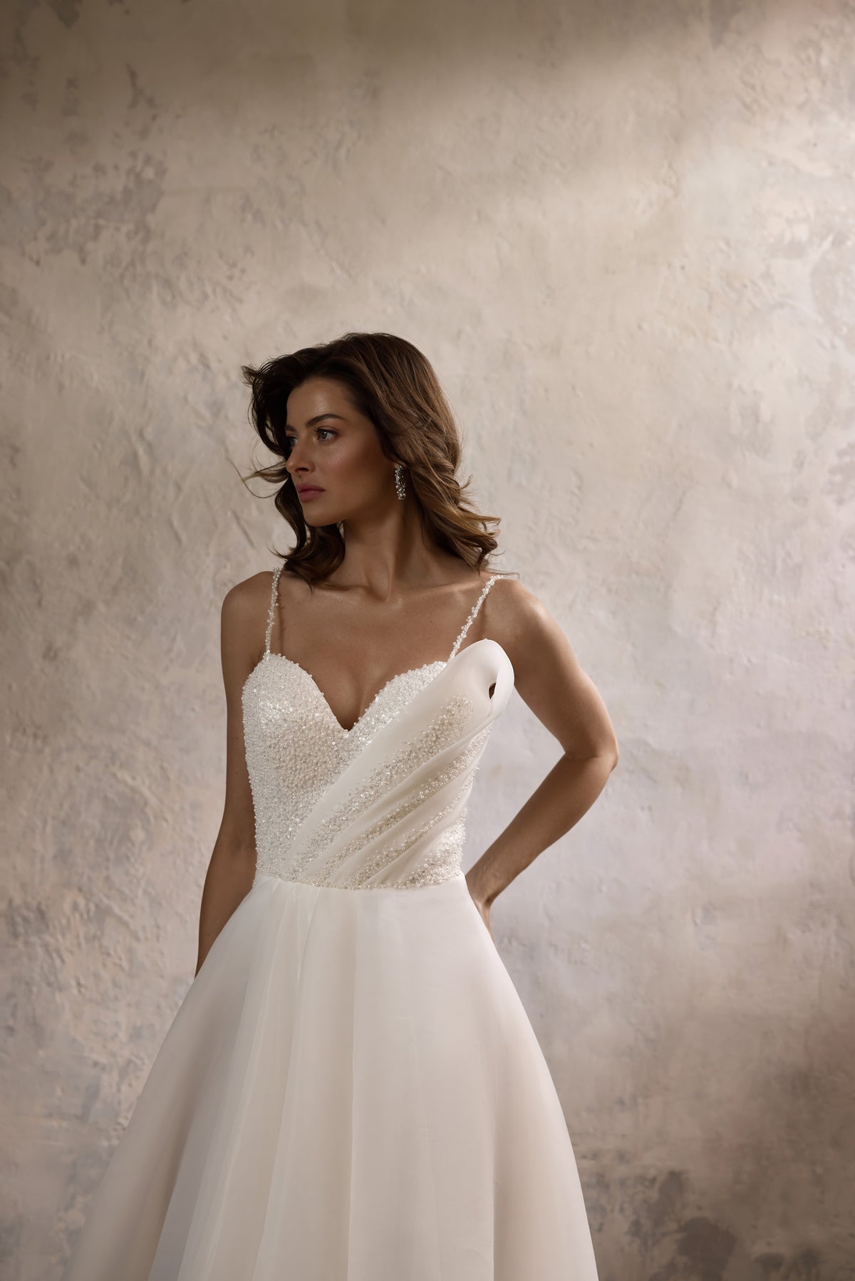Ivory A-line wedding dress with a beaded sweetheart bodice, thin straps, and a flowing skirt