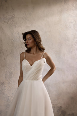 Ivory A-line wedding dress with a beaded sweetheart bodice, thin straps, and a flowing skirt