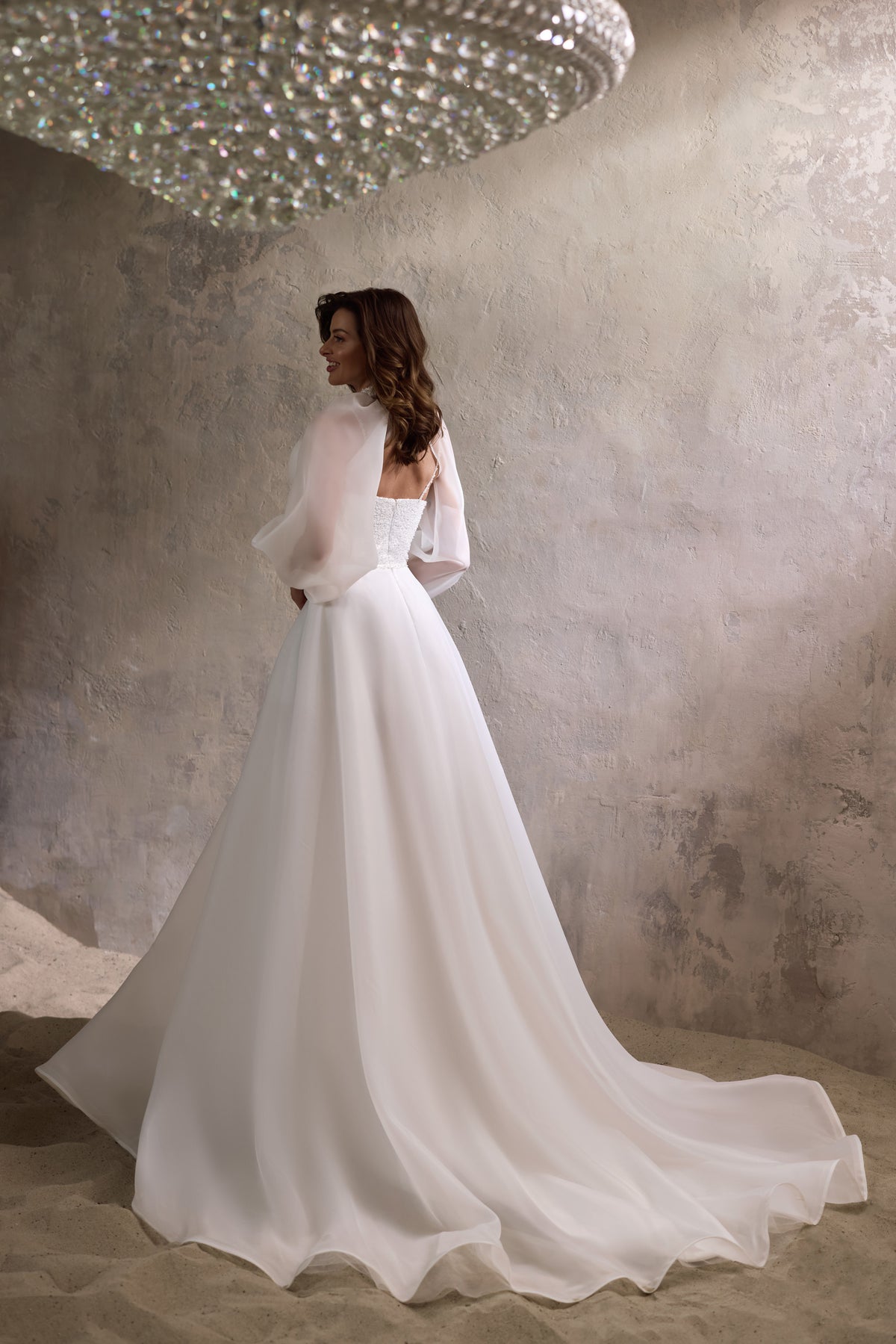 Back view of an ivory wedding dress with a low back, flowing A-line skirt, and sweeping train