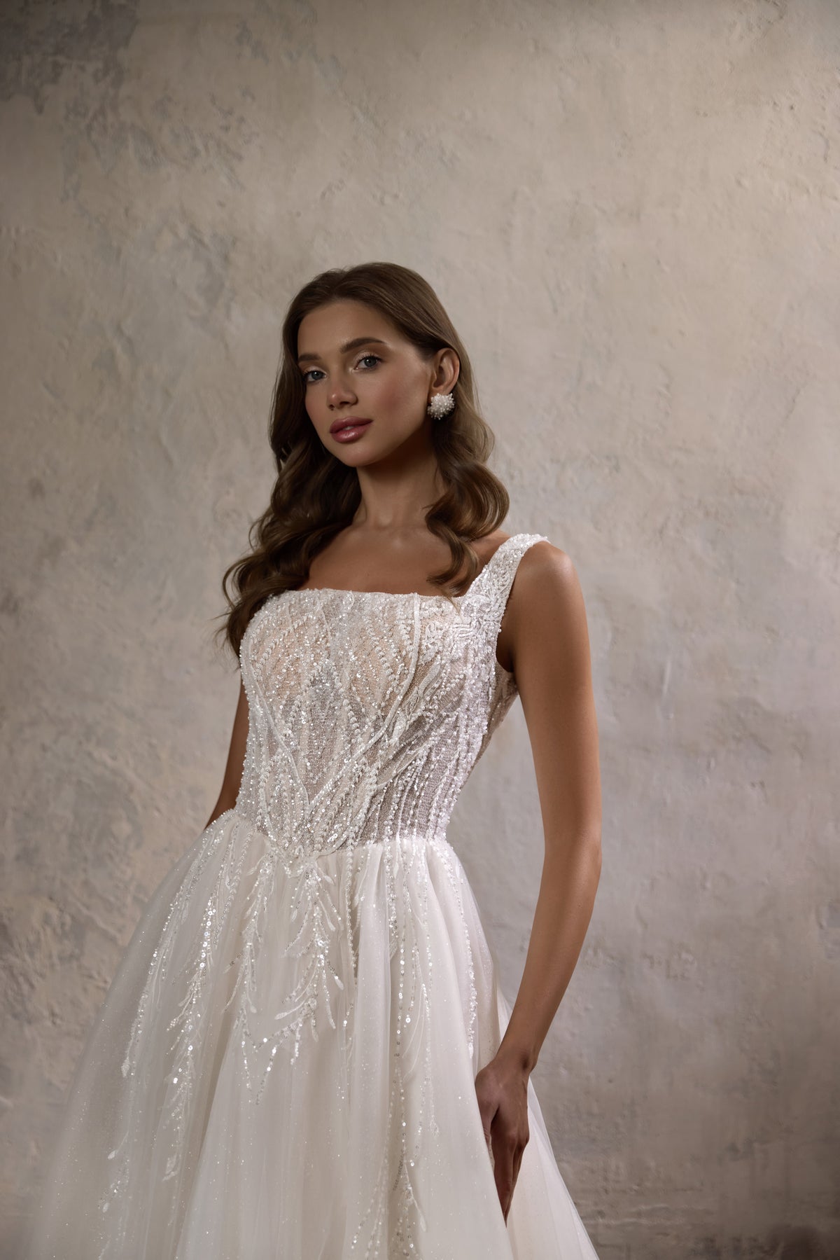Ivory A-line wedding dress with a beaded square neckline, wide straps, and a sparkling bodice