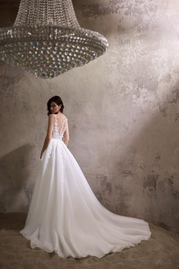 Open lace back and flowing train on an ivory A-line wedding dress