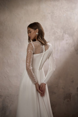 Close-up of the ivory wedding dress back with a sheer beaded sleeve and covered buttons