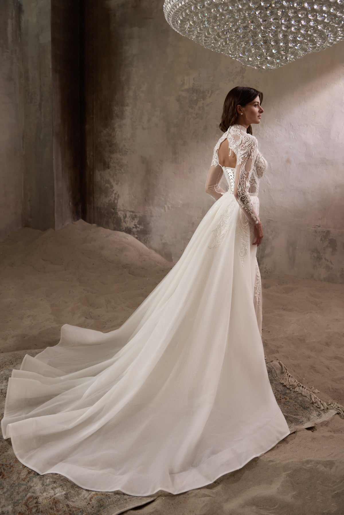 Ivory wedding dress shown from the back with a sweeping detachable overskirt and long train