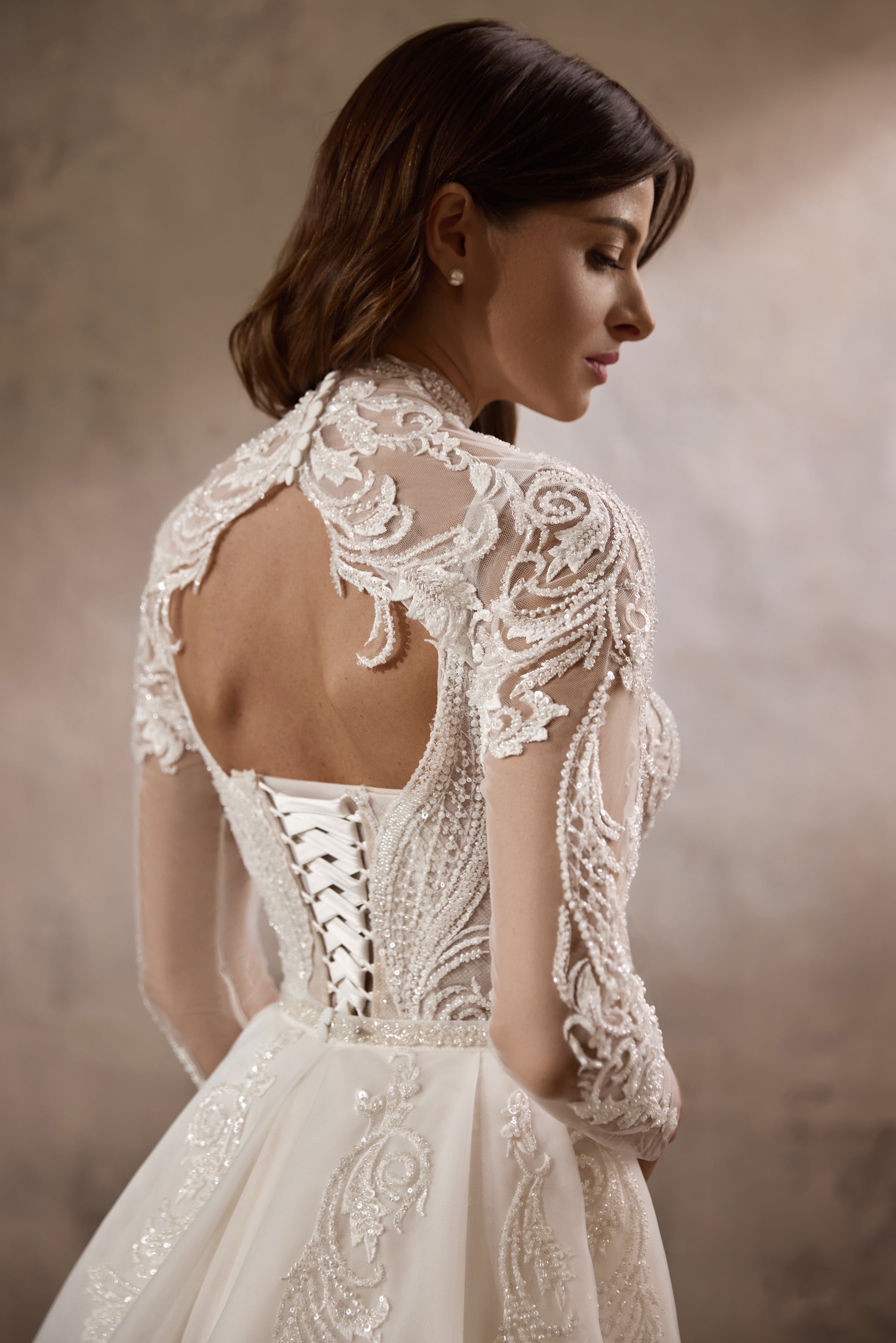 Open lace-up back with sheer lace sleeves on an ivory wedding dress and lace bolero