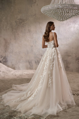 Back view of an ivory wedding dress with floral appliqués, thin straps, and a long flowing train