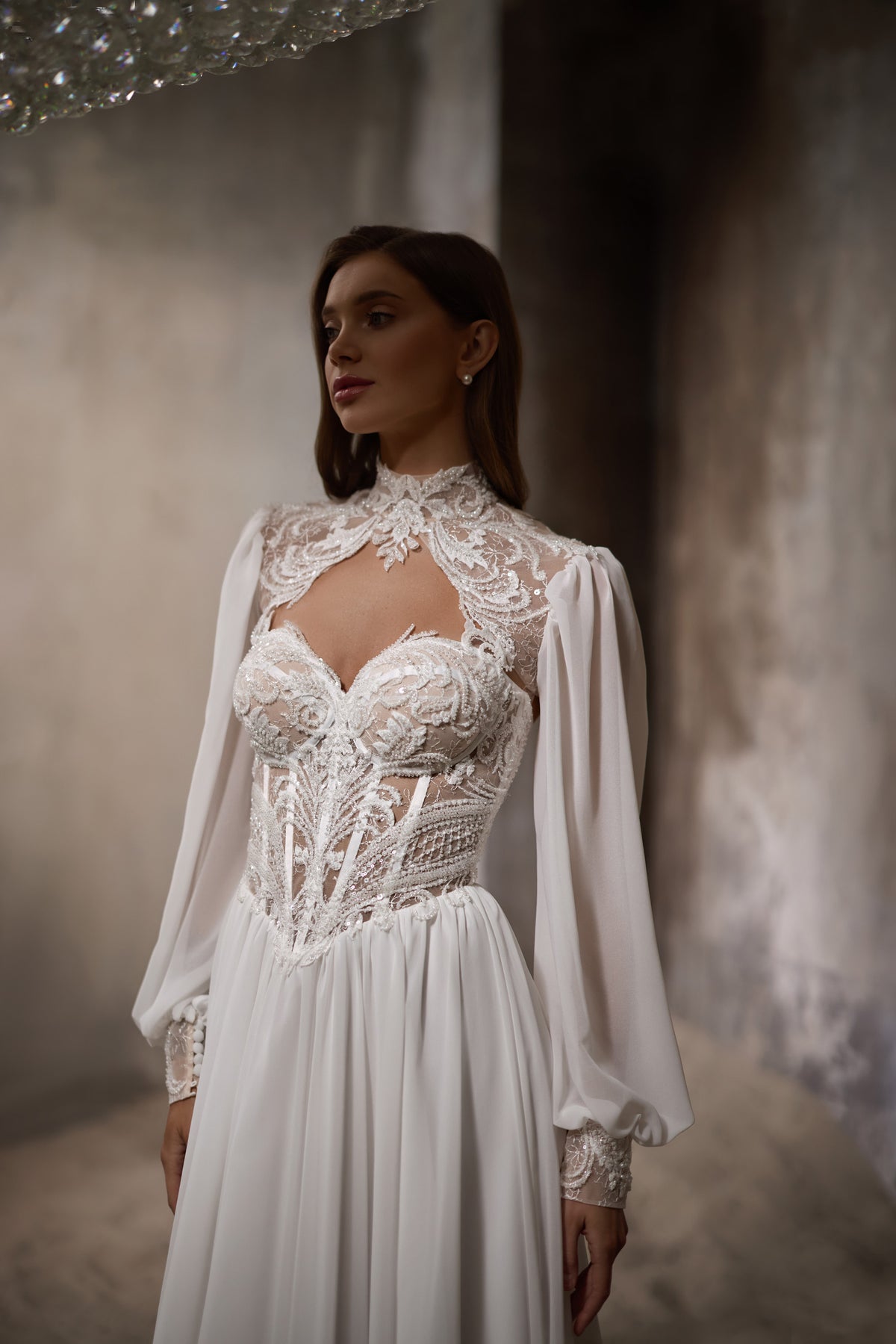 Close-up of an ivory wedding dress with a high lace neckline, sheer cutout, and puff sleeves