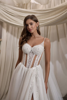 Close-up of an ivory wedding dress with a beaded sweetheart neckline, corset panels, and thigh-high slit