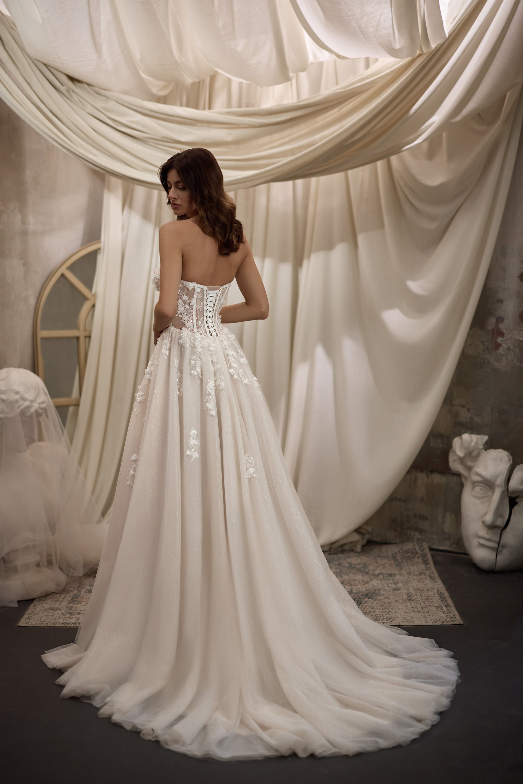 Ivory wedding dress with a corset-style back, floral appliqués, full A-line skirt, and sweeping train