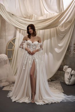 Ivory wedding dress with a sweetheart neckline, floral appliqués, sheer off-shoulder cape, slit, and train