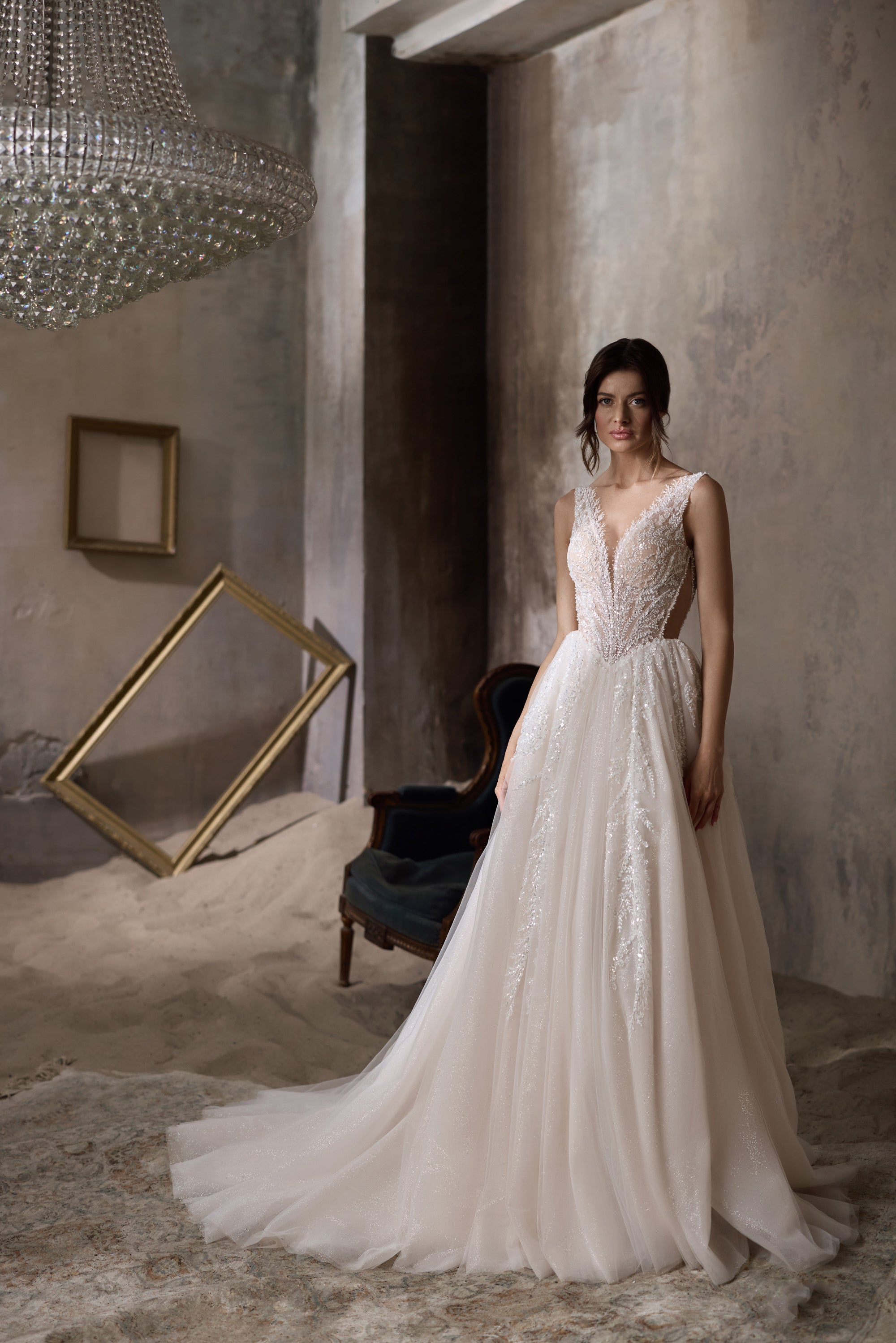 Ivory sleeveless wedding dress with a V-neck beaded bodice, sparkling skirt, and extended train