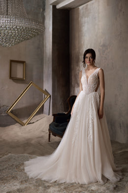 Ivory sleeveless wedding dress with a V-neck beaded bodice, sparkling skirt, and extended train